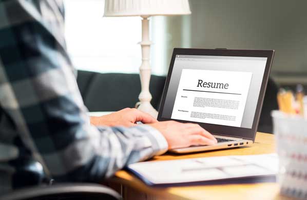 Man writing resume on laptop