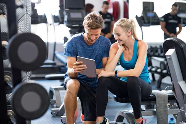 Man and women using tablet in gym