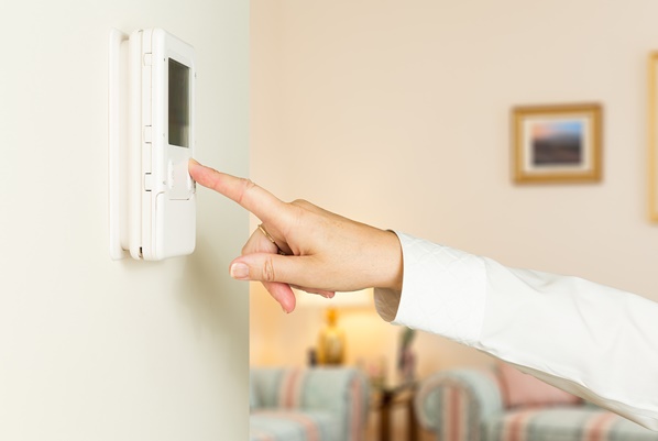 Women setting thermostat in home