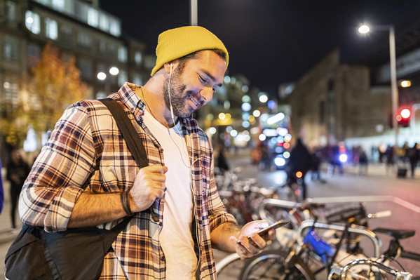 man looking at his phone in city street