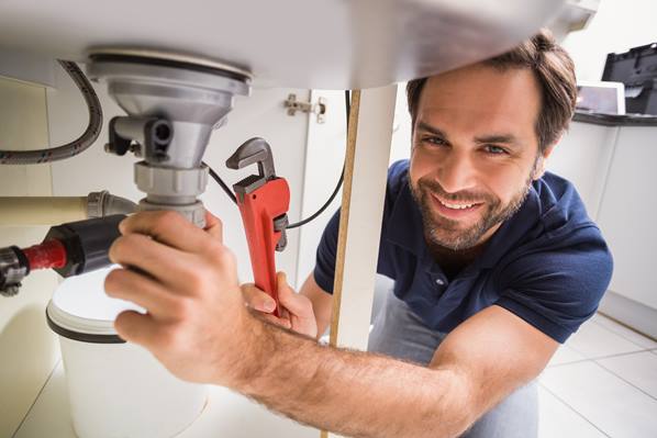 Trades person fixing a leak under sink for customer