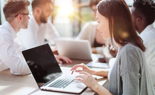 Employee working on computer in office with colleagues